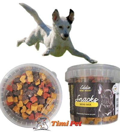 Pas bele boje skače ka EDDIE Semi Moist MINI MIX 200g poslasticama prikazanim iz dva ugla, sa Timi Pet logoom u donjem srednjem delu slike